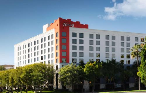 圣安娜Hotel Zessa Santa Ana, a DoubleTree by Hilton的白色的建筑,上面有 ⁇ 红的标志