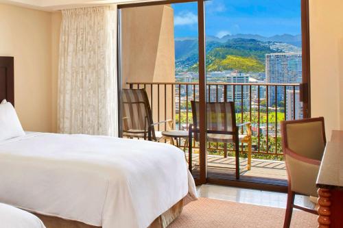 檀香山夏威夷威基基海滩希尔顿度假酒店的一间卧室配有一张床,阳台配有椅子