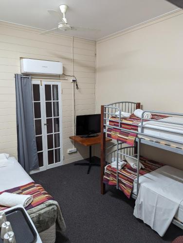 普拉瑟潘GRAND CENTRAL HOTEL PROSERPINE的客房设有两张双层床和一张书桌。