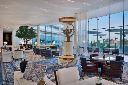 多哈Waldorf Astoria Lusail, Doha的酒店大堂设有桌椅和窗户。