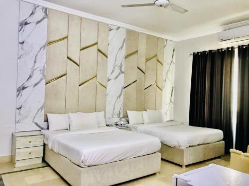 伊斯兰堡Hayat Grand的一间卧室设有两张床和一堵墙