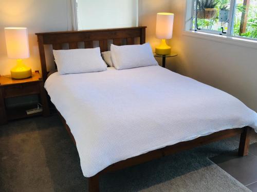 奥克兰海滩山林小屋公寓的一张带白色床单的床和两盏灯