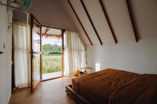 武吉丁宜BAMBOO SHACK的一间卧室设有一张床和一个大窗户