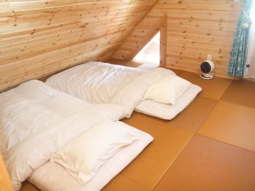 宫古岛島ログ的配有木墙和窗户的客房内的两张床