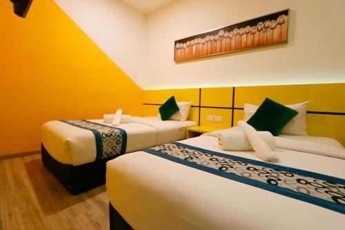 怡保Golden Roof Hotel Sunway Ipoh的黄色墙壁客房的两张床