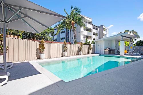 玛志洛银海第六度假村公寓的一个带遮阳伞的游泳池,位于围栏旁