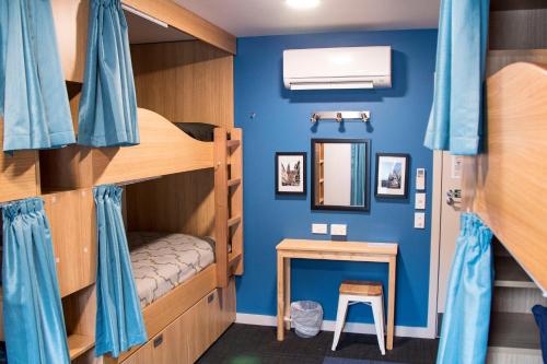 皇后镇Adventure Q2 Hostel的客房设有双层床、桌子和镜子。