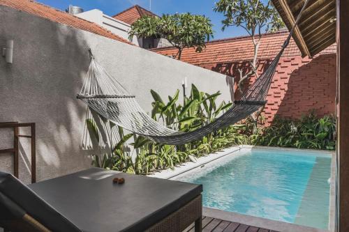 坎古Manca Villa Canggu by Ini Vie Hospitality的游泳池旁墙上的吊床