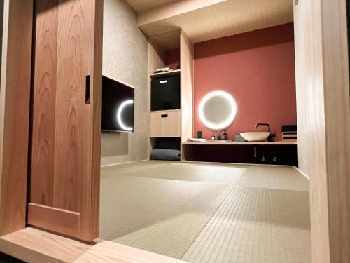 松江市FUMAI sauna &INN-遠赤外線サウナ-松江の歴史と文化と共に過ごすsmart hotel的通向粉红色墙壁的房间的开放式门