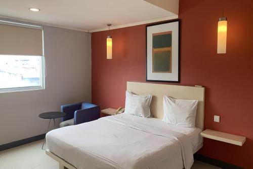 雅加达Hotel Glodok Plaza的卧室配有白色的床和蓝色椅子