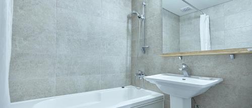釜山塔山酒店的浴室配有盥洗盆、卫生间和浴缸。