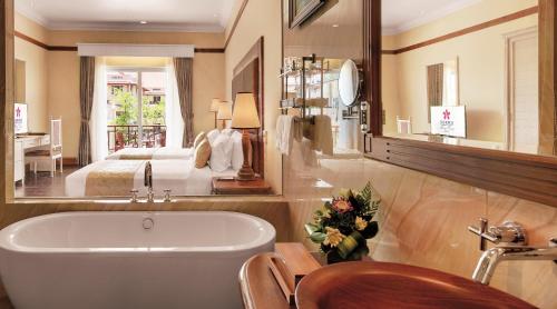 暹粒索卡暹粒度假会议酒店的带浴缸的浴室和1间带1张床的卧室
