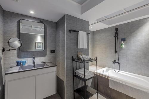 高雄西悠巢旅-高雄车站馆的一间带水槽、浴缸和镜子的浴室