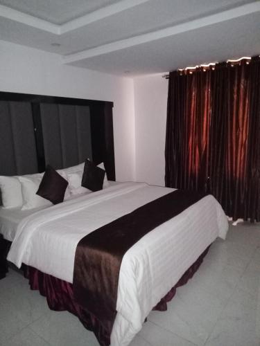 拉各斯Jada Lifestyle & Lounge的卧室配有一张带黑色窗帘的大型白色床