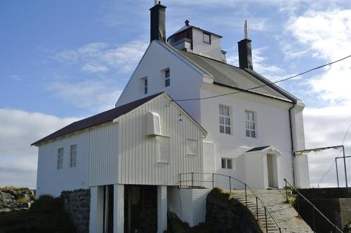 VærøyLofoten Fyr的一座白色的建筑,上面有一座塔