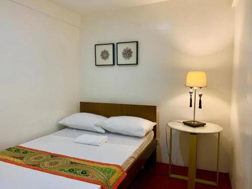 马尼拉Courtyard Hotel的一间卧室配有一张床和一张桌子上的台灯
