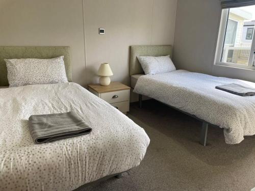 佩文西42 Woodland Walk Pevensey Bay Holiday Park sleeps 6的一间卧室配有两张床和一张带台灯的桌子