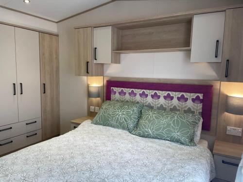 佩文西74 Bayside Cove Pevensey Bay Holiday Park的一间卧室配有一张带紫色床头板的床