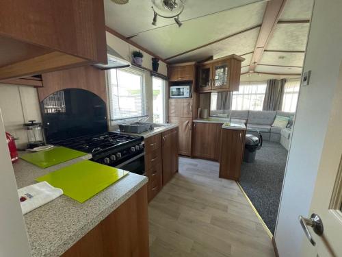 佩文西27 Tower View Pevensey Bay Holiday Park的厨房配有木制橱柜和炉灶烤箱。