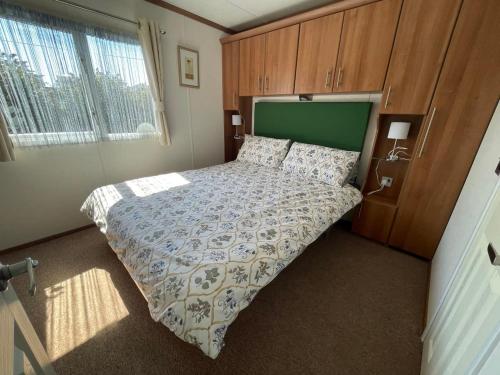 佩文西27 Tower View Pevensey Bay Holiday Park的一间卧室配有一张大床和绿色床头板