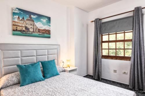 马佐Lightbooking Luymar Villa de Mazo con piscina的一间卧室配有一张带蓝色枕头的床和一扇窗户。