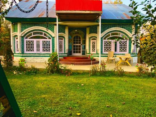 古尔马尔格Habib Guest House (Gulmarg)的绿色白色的房屋,有红色的屋顶