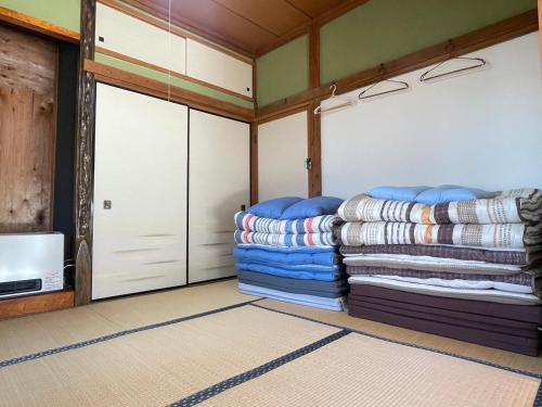 Nishiwada農家古民家ねこざえもん奥屋敷 Nekozaemon-Gest house的一间设有两个车库门和一堆毯子的房间