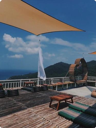 涛岛Exotic Stay Koh Tao的一个带椅子和桌子的甲板以及一把雨伞