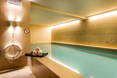 阿姆斯特丹Pestana Amsterdam Riverside的浴室内设有一个带浴缸的浴室的游泳池