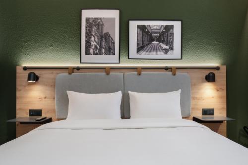 尼姆钟楼尼姆中央玛加博内尔酒店的卧室配有一张大床,墙上挂有三幅画