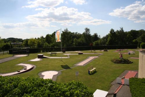 VersmoldPension / Gaststätte zum Minigolfplatz的草地上设有长椅和旗帜的公园