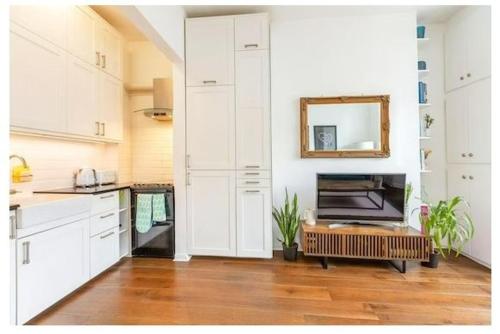 伦敦Stylish, 2 Bed Apartment, Muswell Hill的厨房配有白色橱柜和墙上的镜子