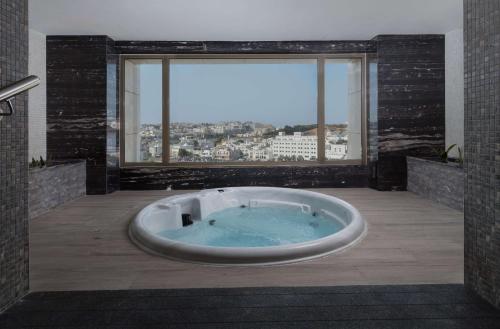 马斯喀特DoubleTree by Hilton Muscat Qurum的设有带大浴缸的浴室和大窗户