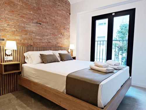 略夫雷加特河畔奥斯皮塔莱特ARIQUS Fira Apartments的一间卧室设有一张带砖墙的大床