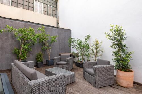 里斯本Bica FLH Suites的庭院里一排柳条椅和盆栽树木