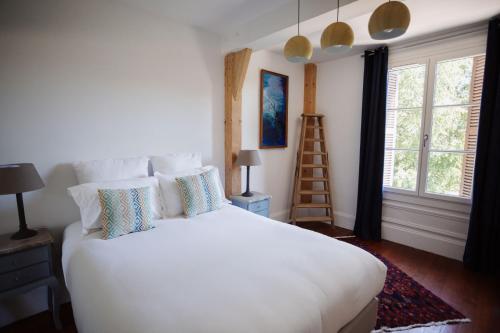翁弗勒尔Demeure du Haut Canteloup的卧室配有带枕头和梯子的白色床。