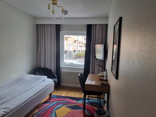 米约尔比Mjölby Stadshotell的配有一张床、一张书桌和一扇窗户的酒店客房