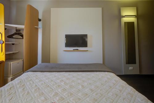 因达亚图巴Rio hotel by Bourbon Indaiatuba Viracopos的卧室配有一张床,墙上配有电视。