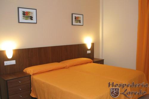 拉卡尔洛塔Hospedería Laredo的一间卧室配有带橙色床单和2盏灯的床。