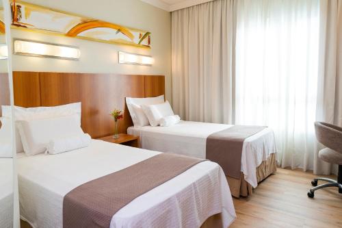 约恩维利Bourbon Joinville Convention Hotel的酒店客房设有两张床和窗户。