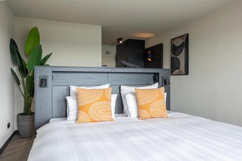 艾默伊登Leonardo Hotel IJmuiden Seaport Beach的一间卧室配有带两个橙色枕头的床