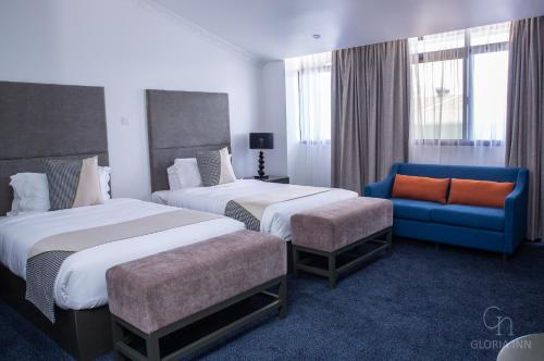 恩多拉Gloria Inn Hotel - Ndola的酒店客房,设有两张床和一张蓝色的沙发