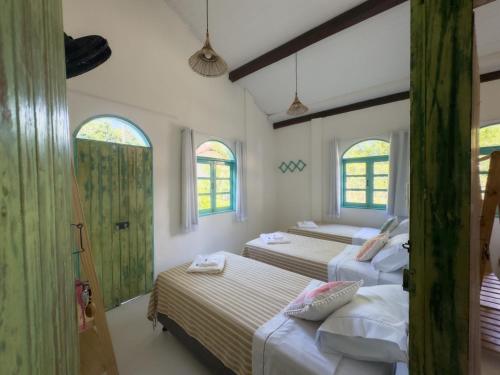 阿拉亚尔达茹达Vila Rita Hostel Arraial d'Ajuda的一间带三张床和两扇窗户的卧室