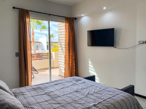 佩尼亚斯科港New Built Condo minutes to Beach!的一间卧室配有一张床和一台平面电视