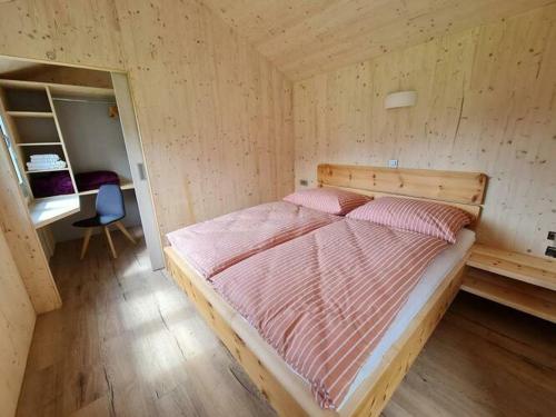 大基希海姆Ferienhaus Woodcube Großkirchheim的卧室配有木墙内的一张床