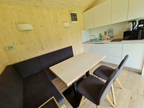 大基希海姆Ferienhaus Woodcube Großkirchheim的厨房配有木桌和2把黑色椅子