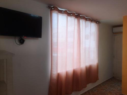 阿塔卡梅斯Hotel Carmita的墙上有电视的窗帘