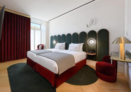 里斯本Montebelo Vista Alegre Lisboa Chiado Hotel的一间卧室配有一张大床和一张红色椅子