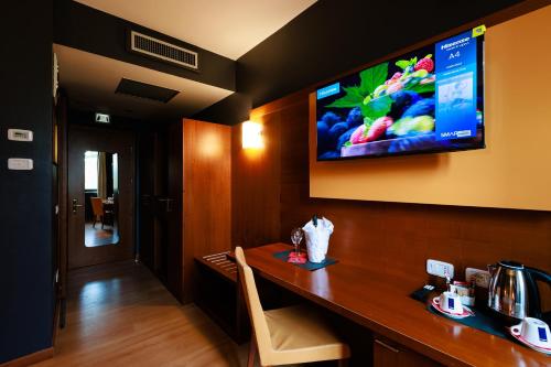 奥莱焦Hotel Villa Delle Rose - Malpensa的酒店客房设有一张桌子,墙上配有电视