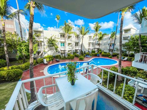 蓬塔卡纳SOL CARIBE DUCASSI STUDIOS Apartments Punta Cana Bavaro BEACH CLUB & SPA的一个带桌椅的阳台和一个游泳池